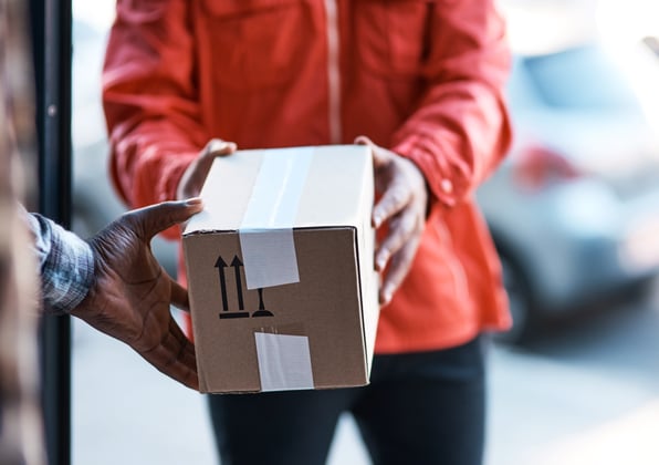 A small box is carefully handed over from one shipment professional to another, indicating the care of shipment protection.