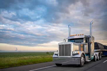 Gray classic American semi truck with covered cargo twilight highway